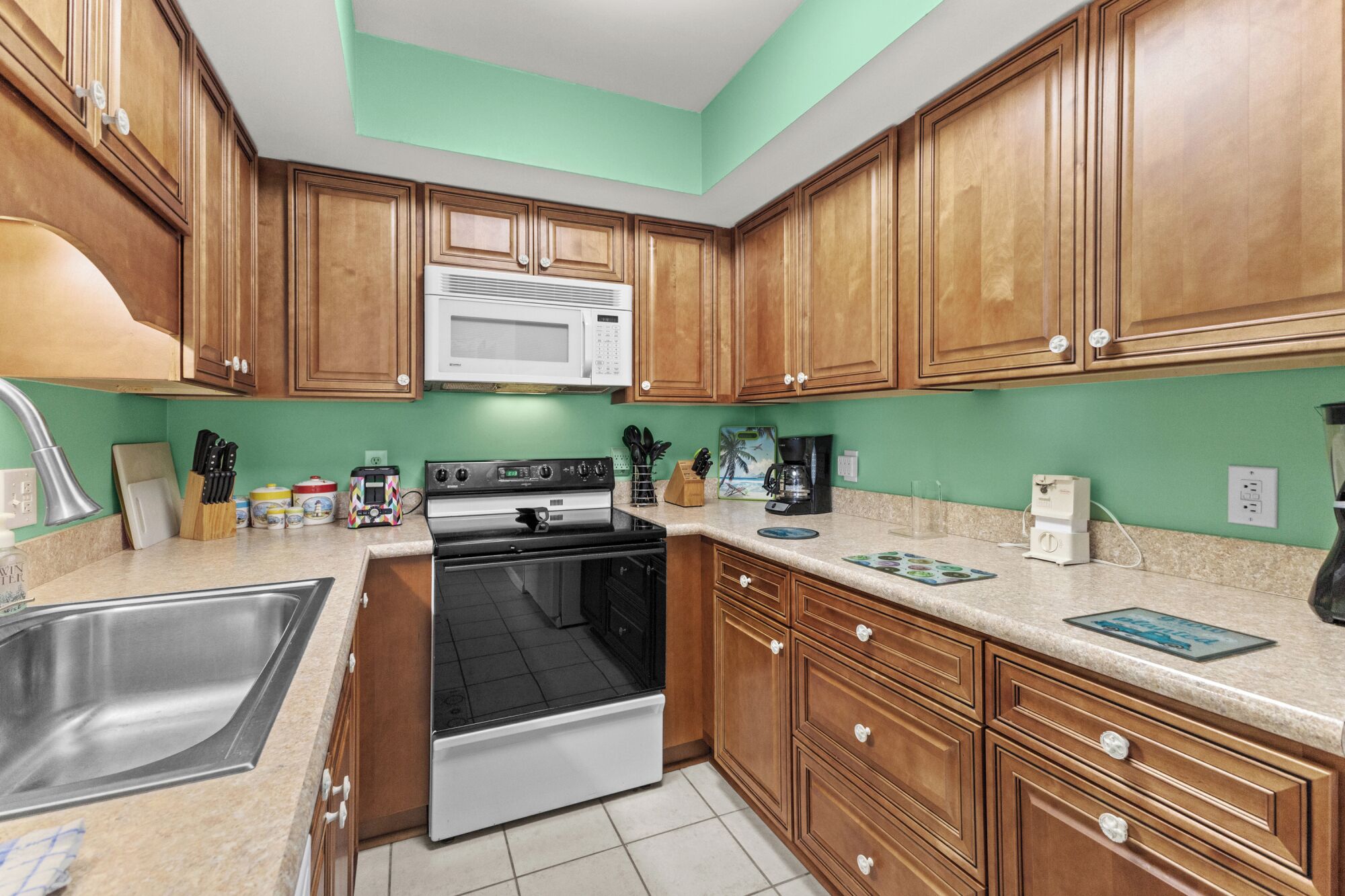 Una cocina con armarios de madera, microondas, estufa y fregadero.