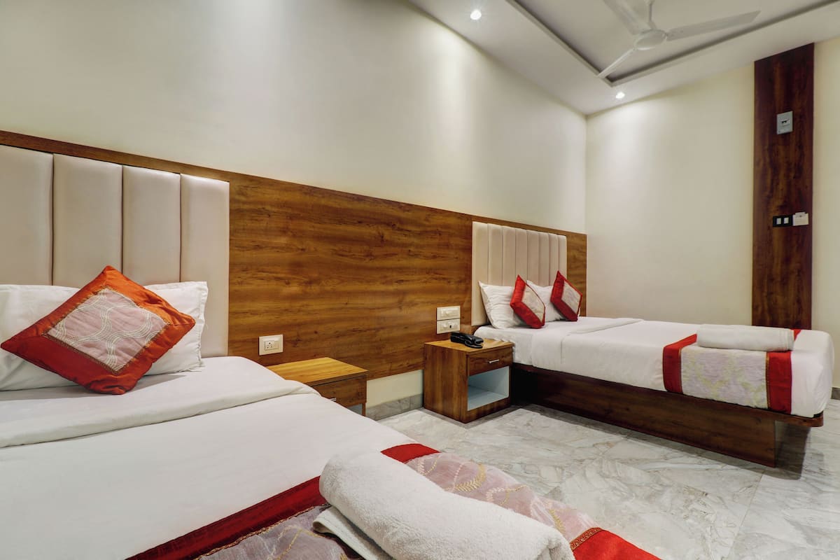 A hotel room with two beds, wooden headboards, white bedding, and a marble floor.