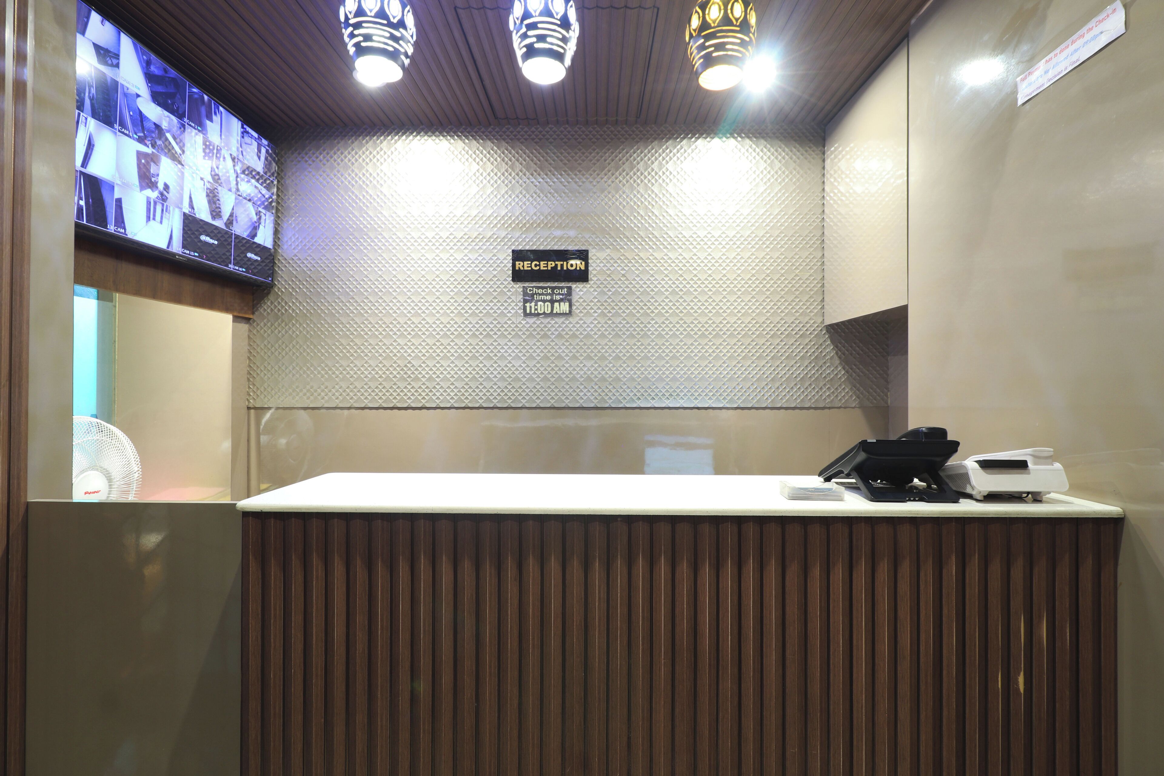A reception area with a check-out counter, a television mounted on the wall, and a sign indicating the check-out time.