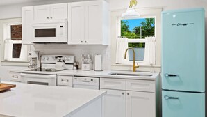 Una cocina moderna con armarios blancos, microondas integrado, estufa y refrigerador azul claro.