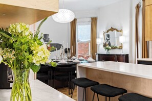 Una cocina moderna con encimera blanca, taburetes negros y un jarrón de flores.