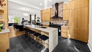 Una cocina moderna con una isla central, armarios de madera, una estufa negra y una pared de ladrillo.