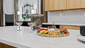 Una encimera de cocina con una bandeja de frutas, una botella de champán y una copa de vino.