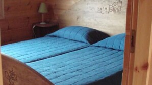 A wooden bed with a blue bedspread in a room with wooden walls. - Detached chalet on a farm in the Jura (Lent)