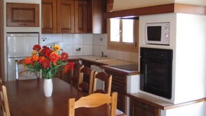A kitchen with wooden cabinets, a microwave, and a sink. - Detached chalet on a farm in the Jura (Lent)