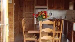 A wooden interior with a dining table and chairs, a kitchen area with cabinets, and a tiled floor. - Detached chalet on a farm in the Jura (Lent)