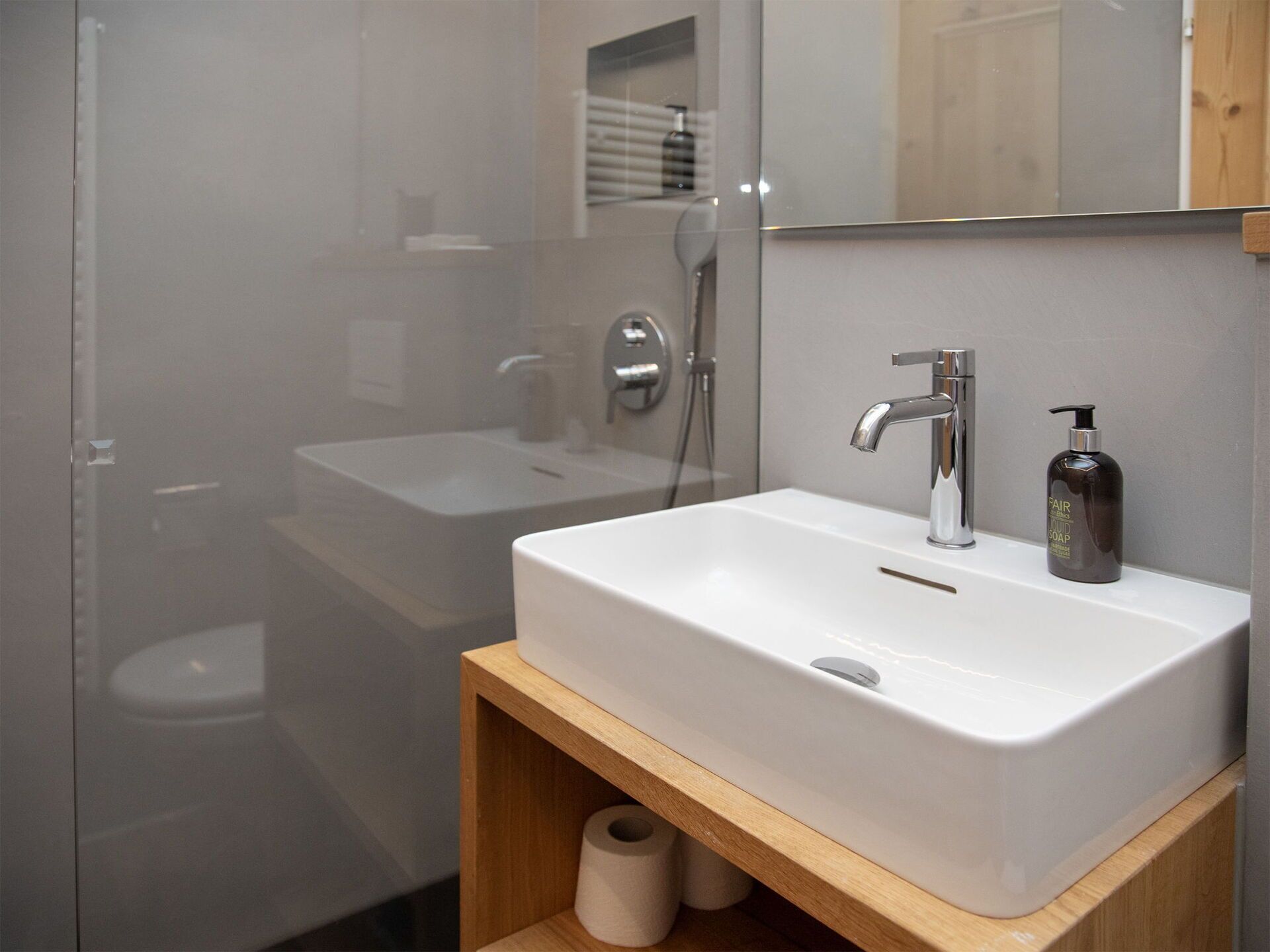 Une salle de bain moderne avec un lavabo blanc, un miroir et une douche.