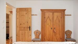 A bedroom with a bed, two wooden chairs, a wardrobe, and a coat rack. - Beautiful apartment for 5 people with pool, WIFI, TV, balcony and panoramic view (Falera)