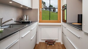 A modern kitchen with a window, white cabinets, a black countertop, and a small radiator. - Beautiful apartment for 5 people with pool, WIFI, TV, balcony and panoramic view (Falera)
