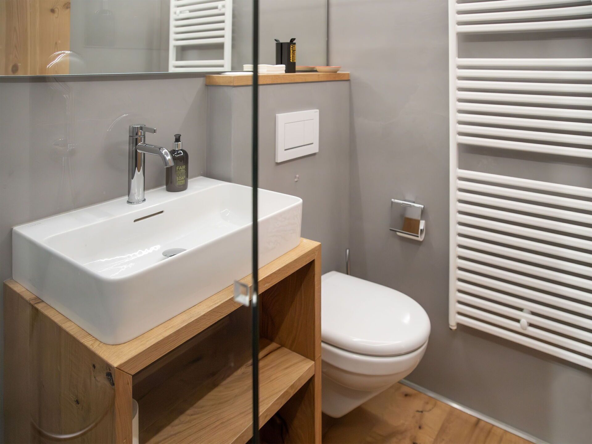 A modern bathroom with a white sink, a mirror, and a toilet.