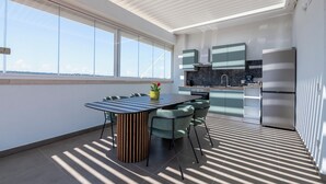 A modern kitchen with a dining area, large windows, and a view of the city.