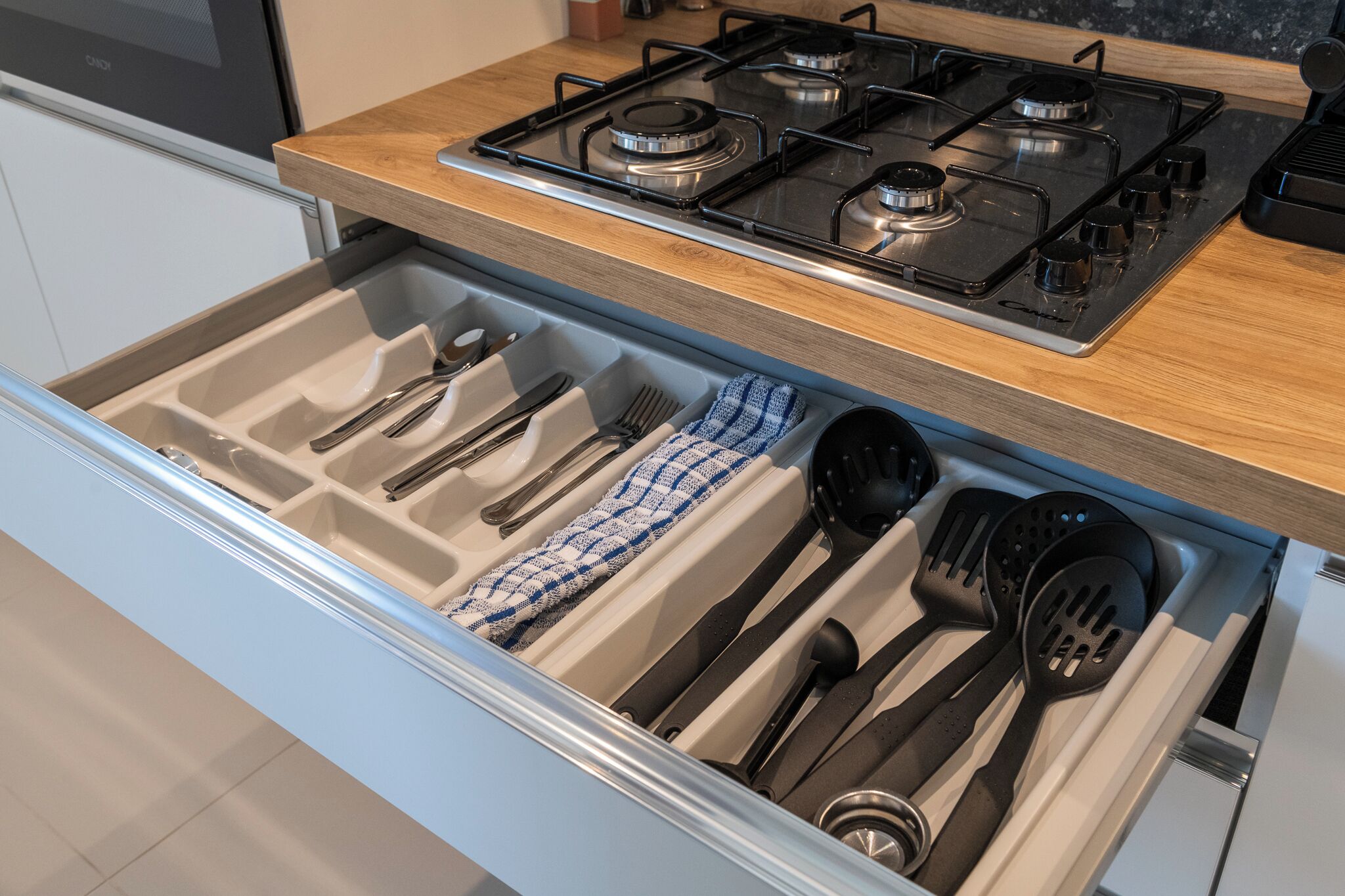 Un cajón de cocina con utensilios y una estufa.