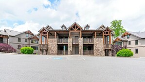 A multi-story hotel with a stone facade, balconies, and a parking lot. - Chalakee Lodge CJ-3- Mountain View, Gated Resort, Indoor/Outdoor Pools & Hot Tub (Boone)