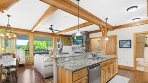A spacious kitchen with granite countertops, wooden cabinets, and a stone fireplace. - Chalakee Lodge CJ-3- Mountain View, Gated Resort, Indoor/Outdoor Pools & Hot Tub (Boone)