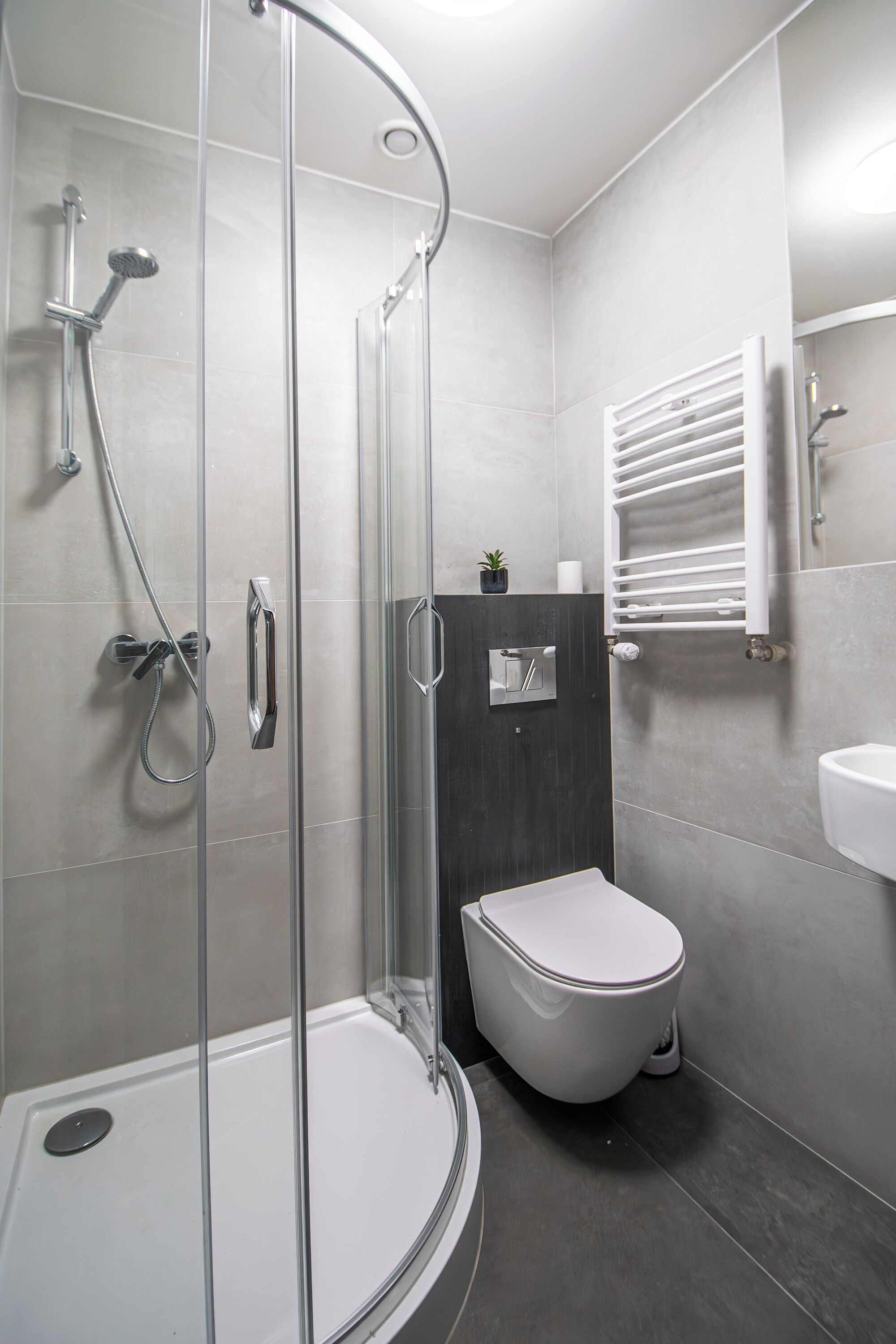 Une salle de bain moderne avec une douche à parois de verre, des toilettes et un lavabo fixé au mur.