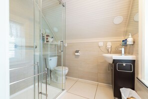 A modern bathroom with a glass shower enclosure, a toilet, a sink, and a vanity. - Les 4 saisons (Québec)