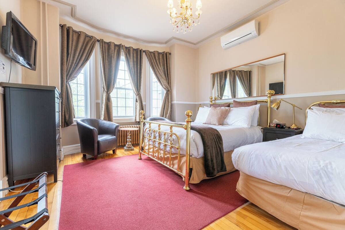 A hotel room with a bed, a chair, a desk, a TV, and a window with curtains.