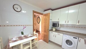 A small kitchen with a dining table, a washing machine, and cabinets. - Lidya's House - 36801 (Entrambasaguas)