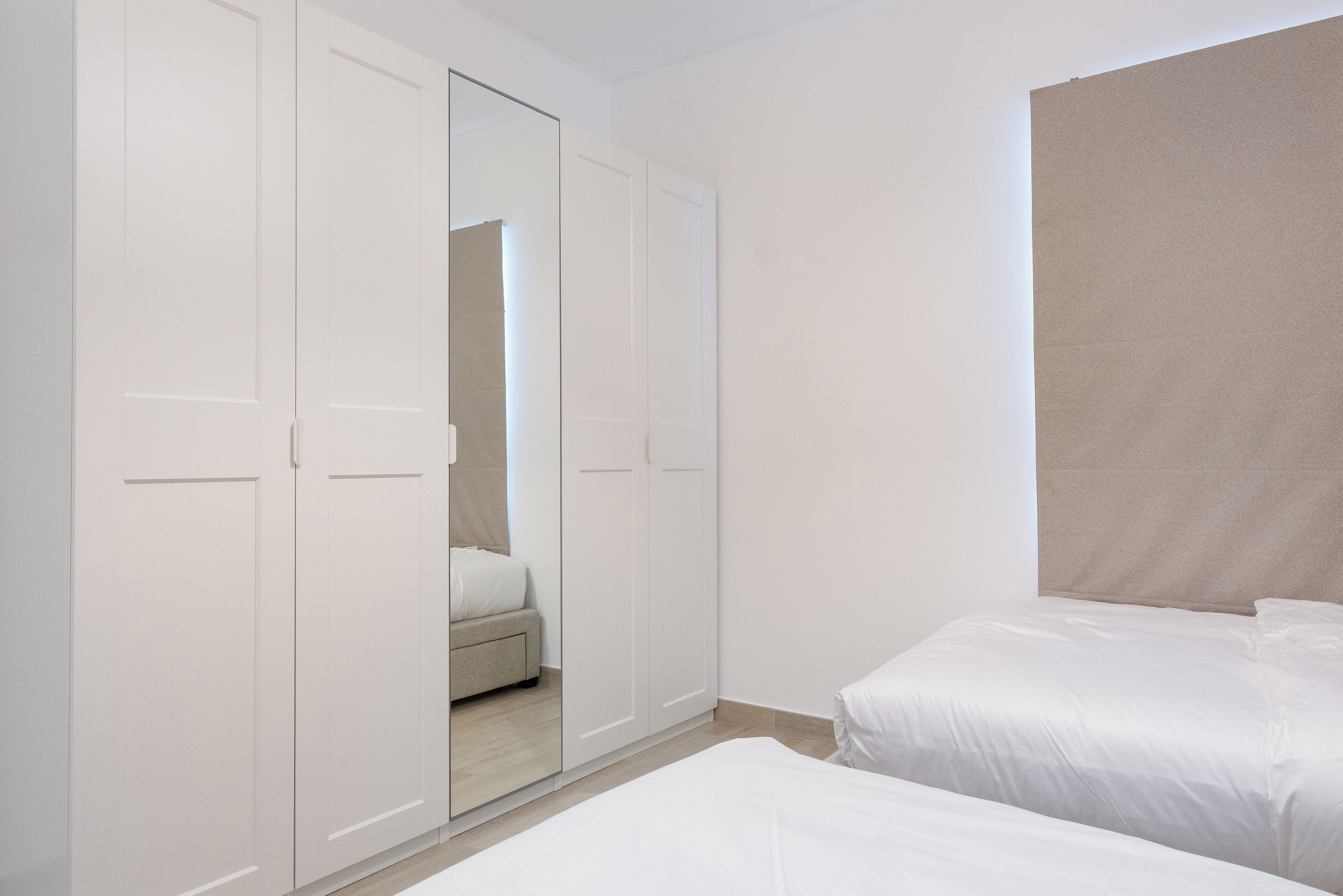 Een slaapkamer met twee bedden, een kledingkast en een spiegel.