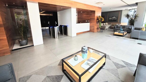 A modern lobby with a reception desk, seating area, and a coffee table.