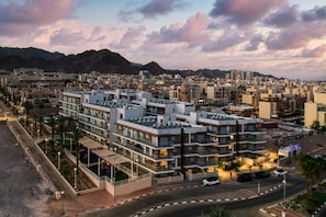 A modern hotel with multiple floors, balconies, and a parking area.