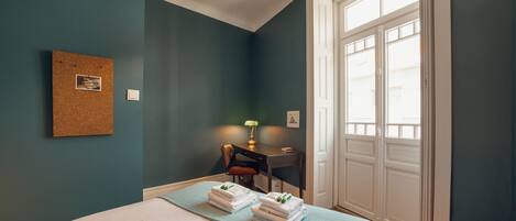 A bedroom with a bed, a desk, a chair, and a window.