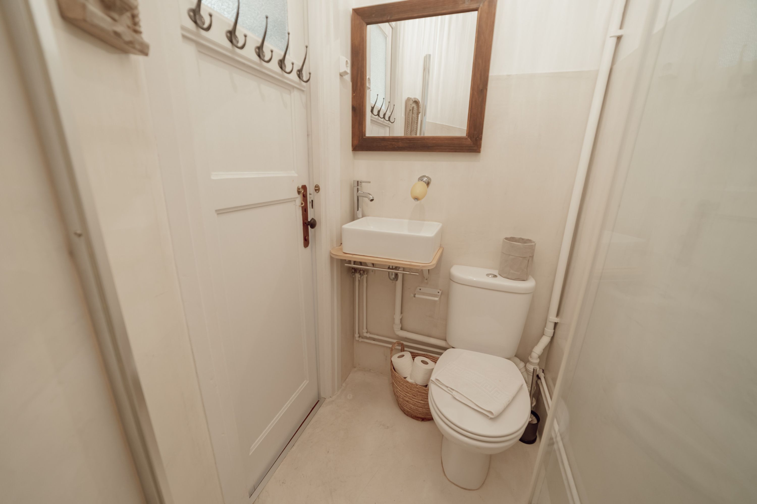 Ein kleines, sauberes Badezimmer mit Toilette, Waschbecken und Spiegel.