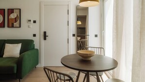 A modern living room with a green sofa, a round wooden table with a bowl, and a pendant light. - Via Monte Apartments by Olala Homes (Madrid)