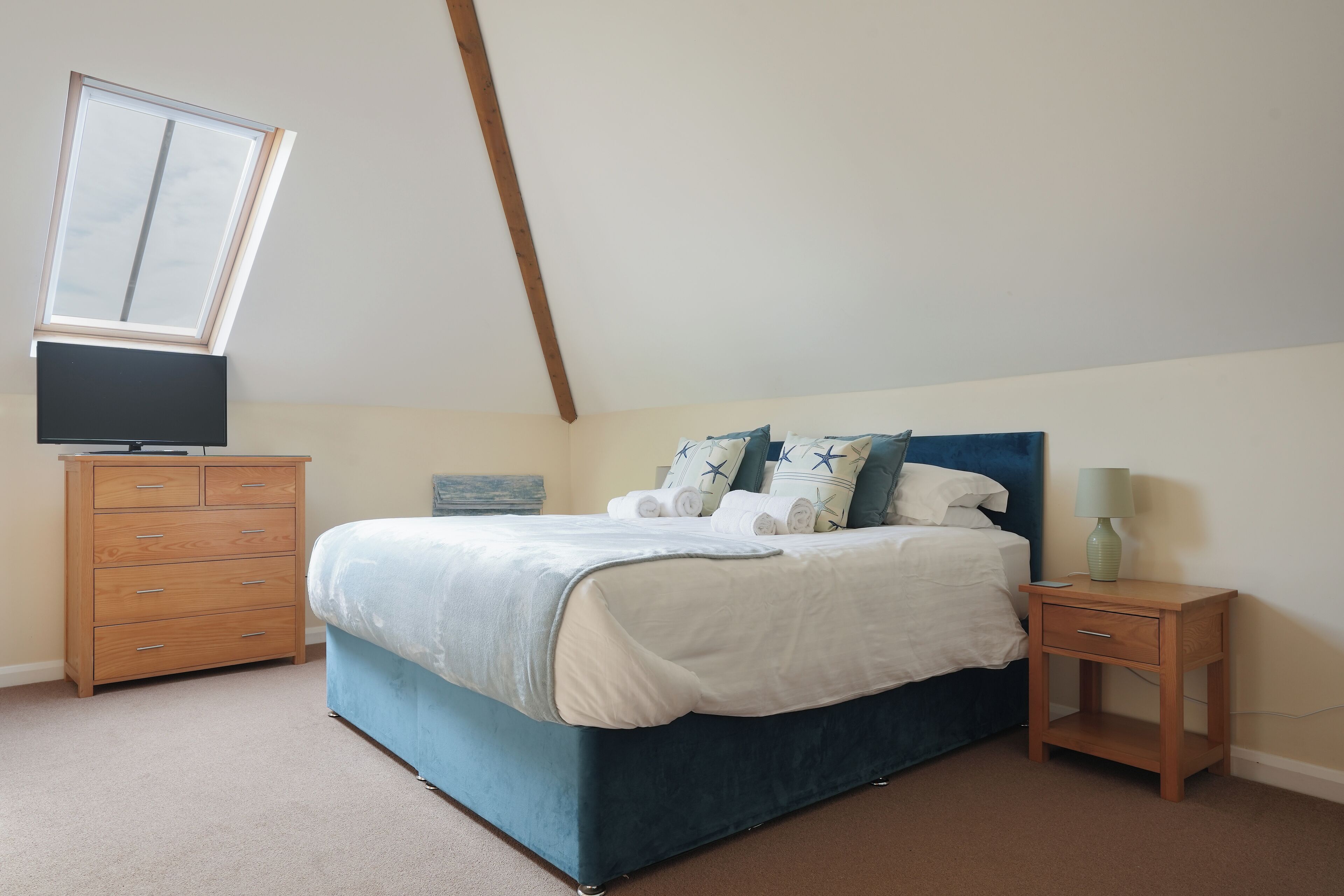 A bedroom with a bed, a dresser, a nightstand, and a window.