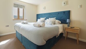 Une chambre avec un grand lit, une table de chevet avec une lampe et une fenêtre donnant sur un beau paysage.