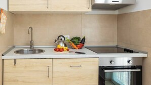 Una cucina moderna con lavello in acciaio inossidabile, bollitore e una ciotola di frutta sul piano di lavoro.