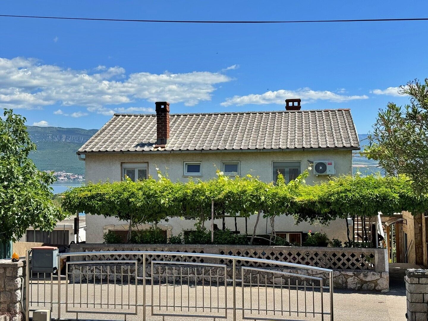 Une maison à deux étages, avec un toit en tuiles, une cheminée et une vue sur la mer.