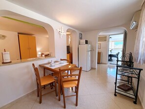 A compact kitchen with a dining area, a refrigerator, and a small dining table with chairs.