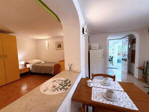 Una habitación de hotel compacta con cama, mesita de noche y una pequeña kitchenette.