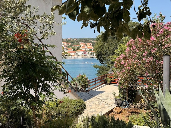 A coastal pathway leading to a body of water with a view of a town in the distance.