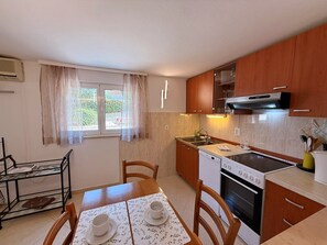 A compact kitchen with wooden cabinets, a stove, and a dining area with a table set for two.