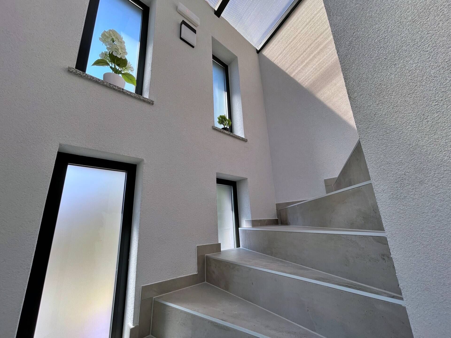 En moderne bygning med en trappe op til anden etage, store vinduer og et minimalistisk design.