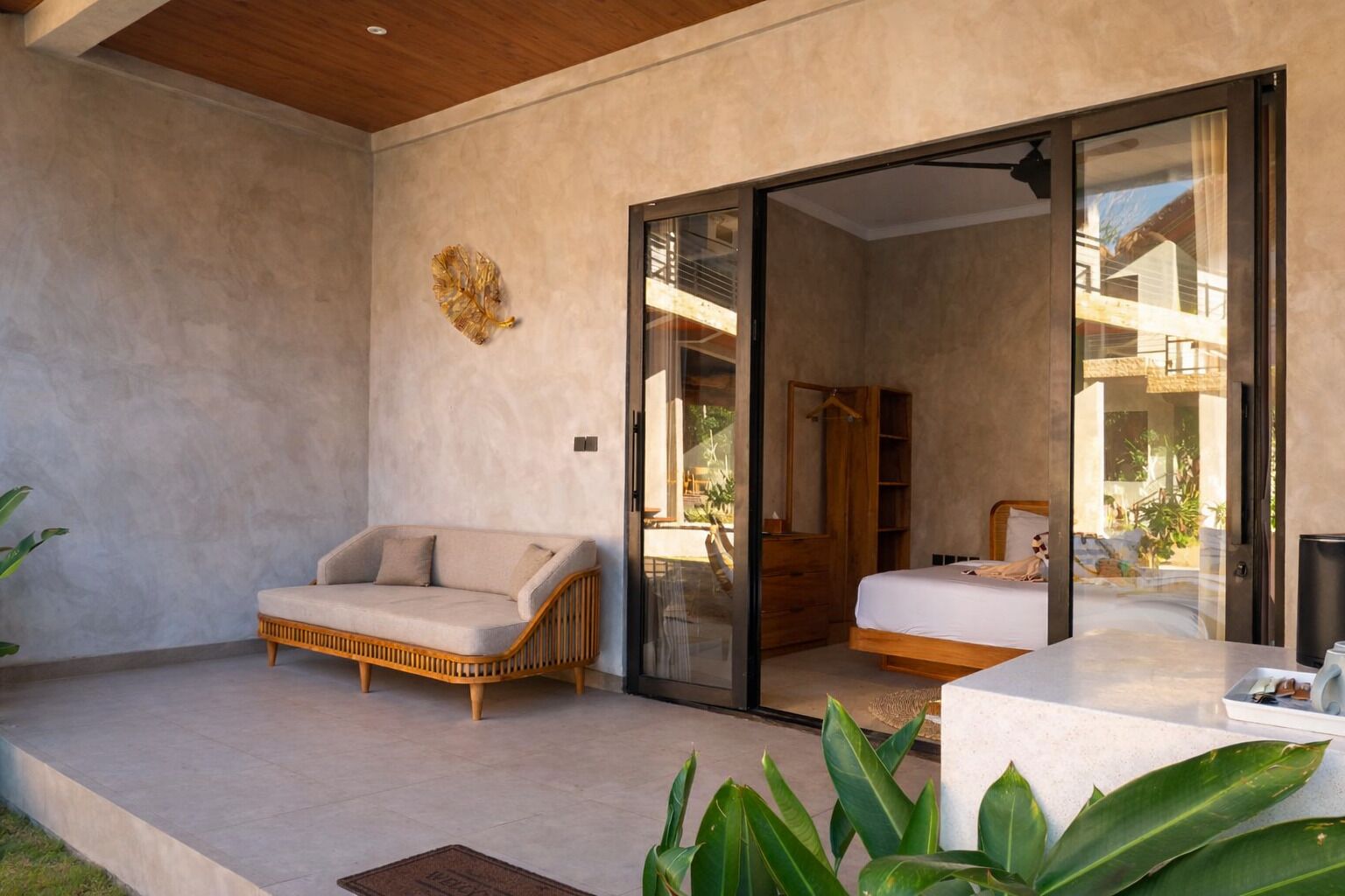 Een moderne slaapkamer met een grote glazen schuindeur die leidt naar een balkon, een bank en een bed.