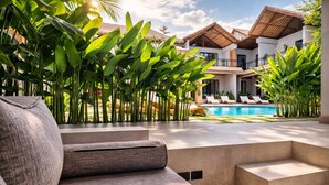 Un espace aménagé au bord de la piscine, avec un canapé, des chaises longues et une piscine.
