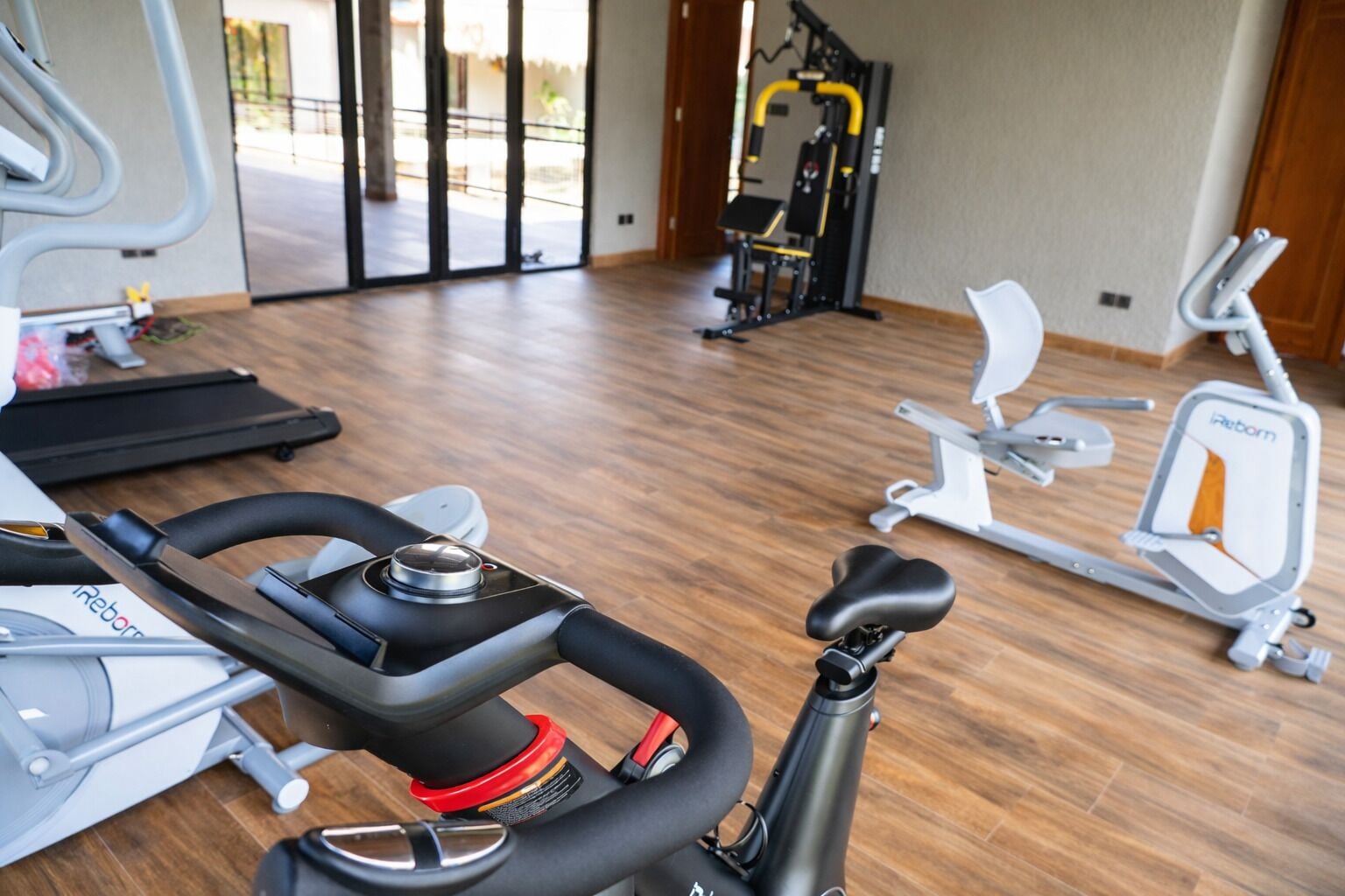 Une salle de sport équipée de divers appareils, notamment un vélo d’appartement, un appareil elliptique et une machine de musculation.