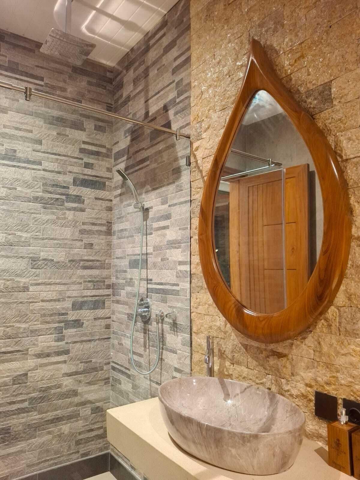 A bathroom with a stone wall, a wooden vanity, and a large mirror.