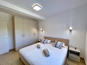 Et hotelværelse med en stor seng, to sengeborde, et garderobeskab og en loftlampe.