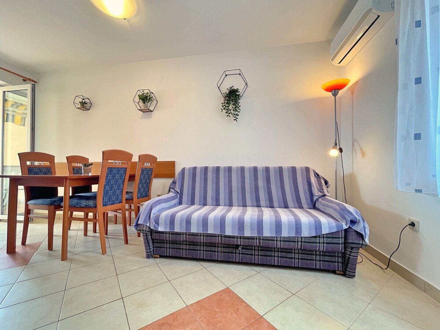 A living room with a sofa, a dining table with chairs, and a floor lamp.