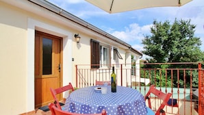 A patio with a round table covered by a blue polka dot tablecloth, surrounded by red chairs. - Apartment Bujas - 160 m from the sea, free parking, BBQ, ground floor (Šilo)