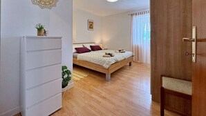 A bedroom with a bed, a dresser, a small plant, and a ceiling light. - Apartment Car - 90 m from the sea, private terrace, parking, BBQ (Šilo)
