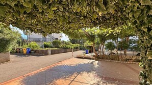 A paved outdoor area with tiled flooring, surrounded by greenery and a stone wall. - Apartment Dragica - sea view, 350 m from sea, balcony, free parking, BBQ (Šilo)