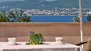 A table set with two cups and a vase with greenery, overlooking a coastal town and mountains. - Apartment Dragica - sea view, 350 m from sea, balcony, free parking, BBQ (Šilo)