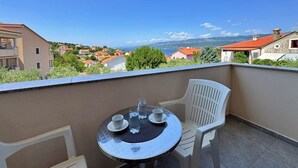 A balcony with a table set for two, overlooking a coastal town with red-roofed buildings and a clear blue sky. - Apartment Dunato I - with sea view, 310 m from the sea, balcony, air conditioning, BBQ (Šilo)