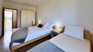 A hotel room with a large bed, bedside tables, a wardrobe, and a balcony door. - Apartment Dunato I - with sea view, 310 m from the sea, balcony, air conditioning, BBQ (Šilo)