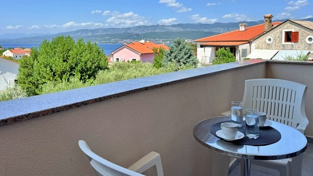 A balcony with a table set for two, overlooking a coastal town with red-roofed houses and a clear blue sky. - Apartment Dunato I - with sea view, 310 m from the sea, balcony, air conditioning, BBQ (Šilo)